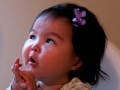 An infant in a high chair focuses her attention on a man sitting next to her.
