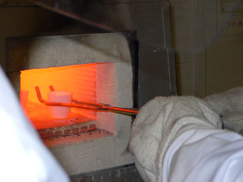 Removing a heated crucible with tongs.