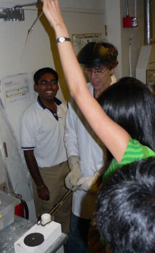 Students draw glass fibers.