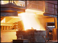 Photo inside the Brackenridge stell mill of a tilted 35-ton electric furnace pouring white-hot steel into a trough below, flying sparks indicate the fluidity of the steel.