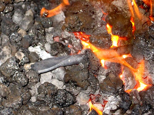The flattened end of a round bar, heating in the fire.