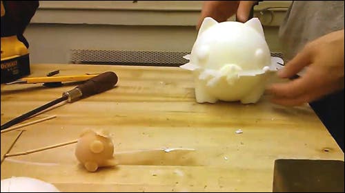 Large white pig with noticeable edges, and a smaller tan pig on a table.