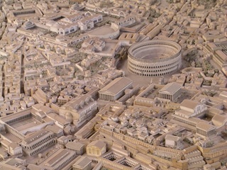 A view of a model of an ancient city, showing a large amphitheater, temples, palaces, and many smaller buildings.