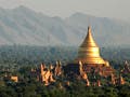 Photo showing many temples and stupas on a plain, with a mountain range in the background.