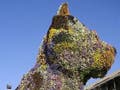 Photograph of a 12-meter-high puppy sculpture covered with flowers.