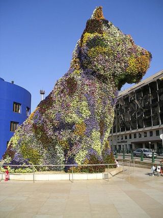 Photograph of a 12-meter-high puppy sculpture covered with flowers.