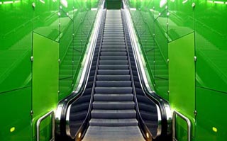 A photo of an escalator with green walls.