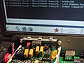 A photo of an exposed circuit board sitting in front of a monitor.