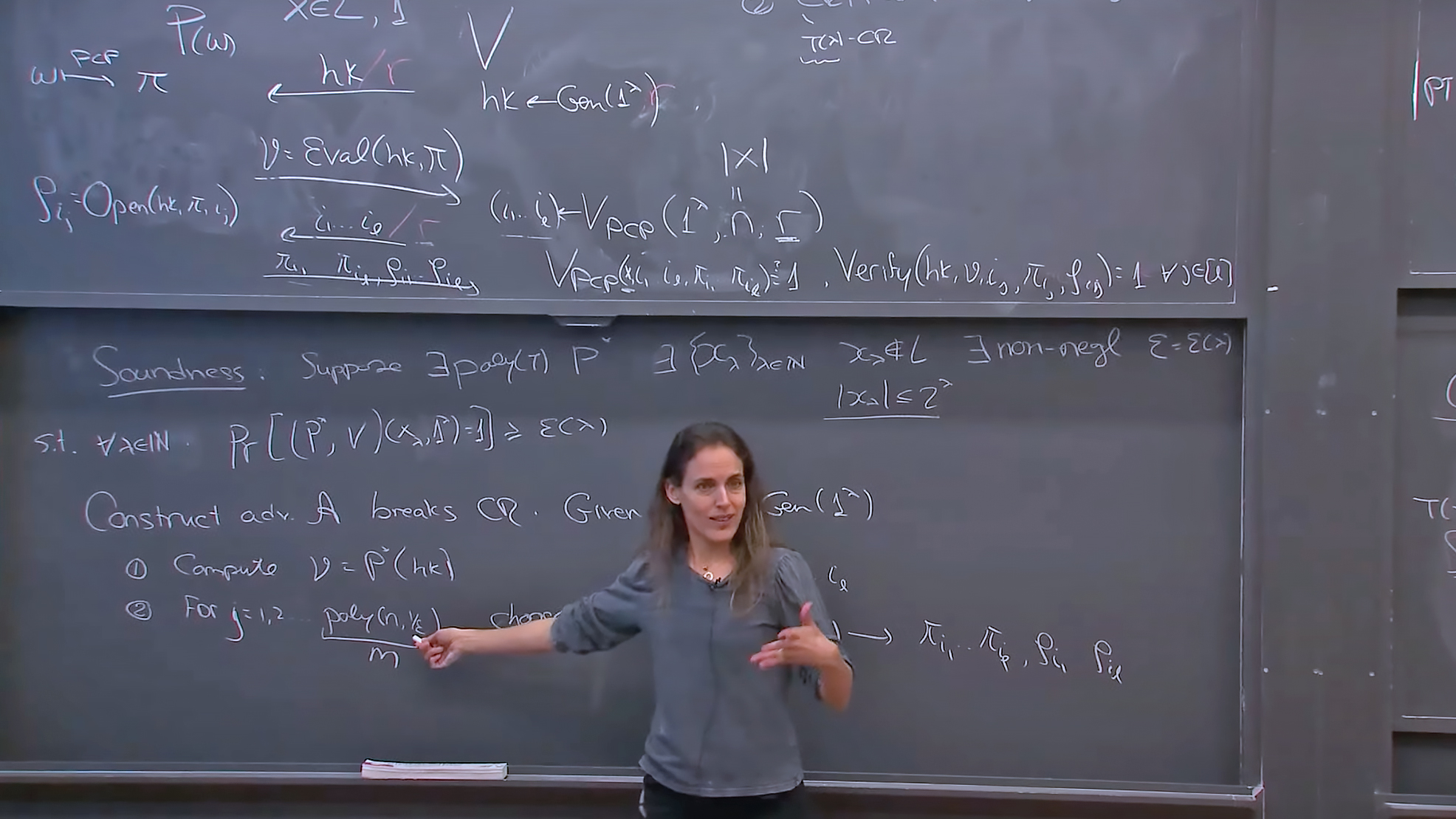 A woman lecturing standing in front of the blackboard with a chalk in her right hand, pointing to the blackboard