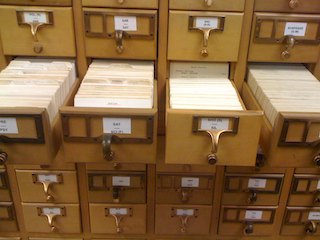 Photograph of a library card catalog with one row of open drawers.