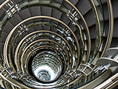 View from the top and down the center of a spiral staircase, made of concrete and glass.