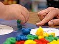 A child sorts colorful toy bears as a teacher looks on.