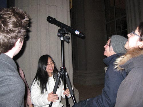 Photo of students setting up a telescope outdoors on a tripod.