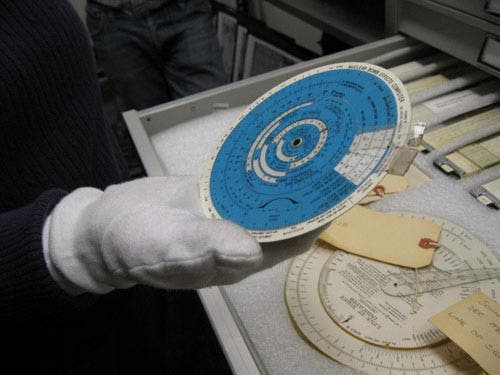 Photo of students holding and viewing circular slide rules in the MIT Museum.