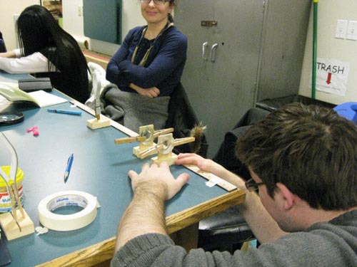 Photo of a student looking through two lenses placed one in front of the other on a table.