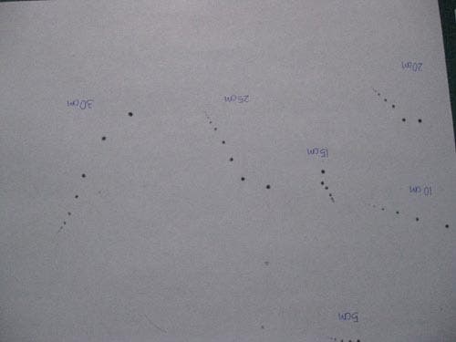 Photo of dark series of marks on a white piece of paper, showing where a ball dropped onto the piece of paper bounced.