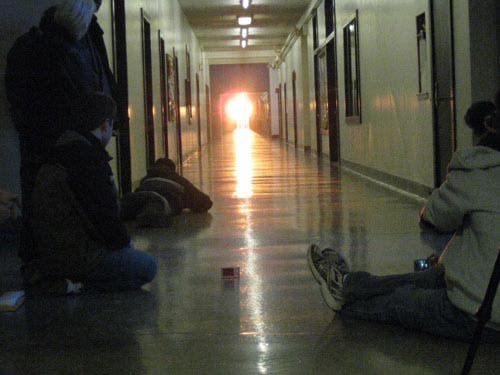 Photo of students on the floor to better observe the effects of the alignment of the sun with the end of the hallway.
