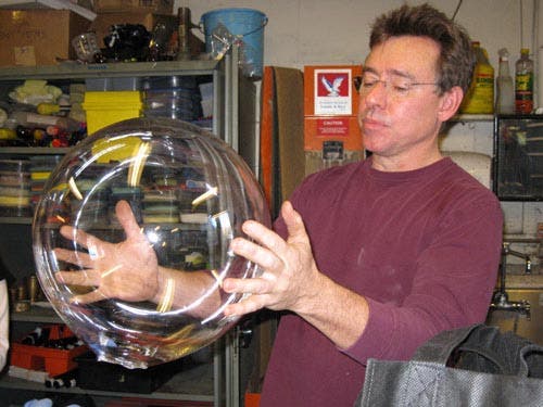 Photo of Peter Houk holding a glass sphere that he made.