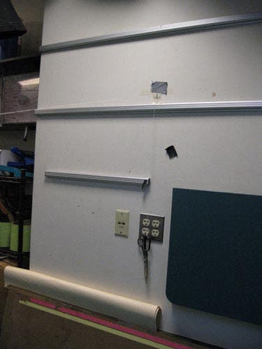 Photo of a scissors hanging from a string attached to the wall by a hook.