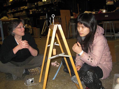 Photo of students observing a simple pendulum made of a block of wood and a string.