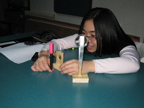 Photo of a student arranging and looking through lenses.