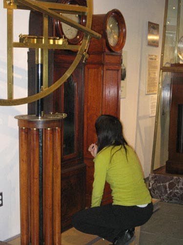 Photo of a student examining a historical grandfather clock.