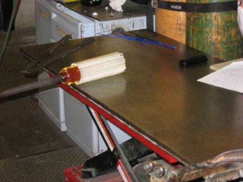 Photo of the hot glass glob with the cool rods being rolled across a metal table.