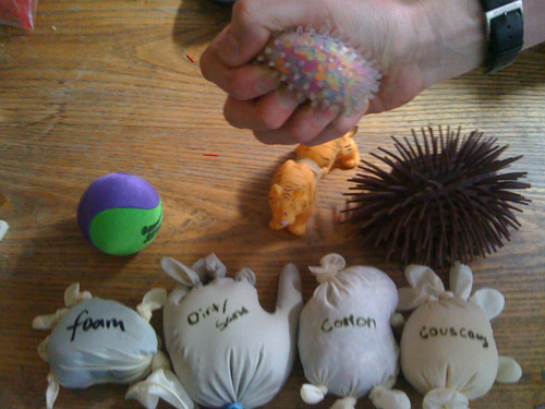 Photo of materials on table, and team member squeezing a toy ball.