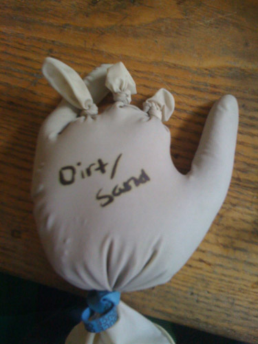 Photo of a disposable glove filled with dirt and sand.