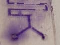 Photo of a glass slide etched with thin channels for fluid movement.