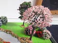 Diorama of a grassy park and trees with water in front.