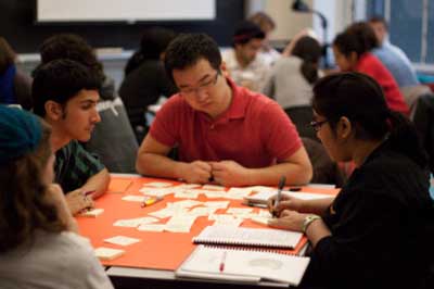 Photo of several students sitting around a table working on small paper cards.