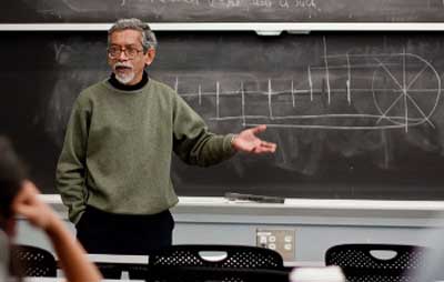 Photo of Suprio Das speaking about a chalkboard drawing of bicycle drivetrain.