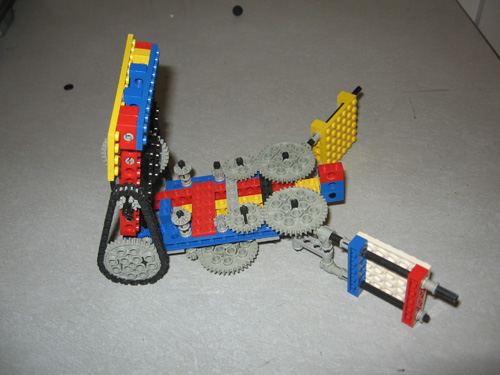 A Lego robot with a claw that opens in the plane of the table, and an arm that rotates perpendicular to the table.