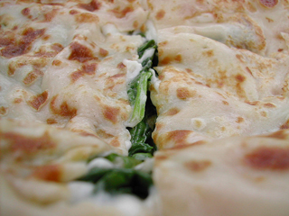 A close-up photo of a thin pancake filled with spinach and cheese.