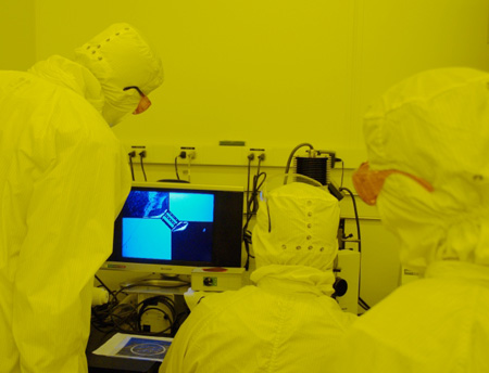 Students view magnified wafer patterns on video microscope.