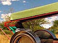 Photo of a two-wheeled ambulance cart attached to rear of bicycle, carrying a reclining patient.