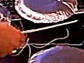 Photo showing hands playing four foil “drums” wired to a computer, with the Scratch cat character animated on screen.
