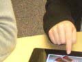 A photo of an autistic boy using an iPad with his teacher.