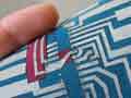Photo of a hand holding a small fabric square with a "printed circuit" pattern of connectors on it.