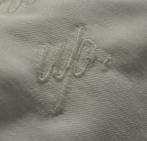 Close-up photo of embroidered word ‘up’ on a white cloth napkin.