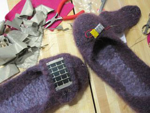 Photo of the slippers: one with the flap open (showing the battery) and one with it closed (showing the solar panel and the diode).