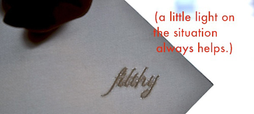 Backlit white embroidered fabric with the word ‘filthy’ in script, and the caption “a little light on the situation always helps.”.