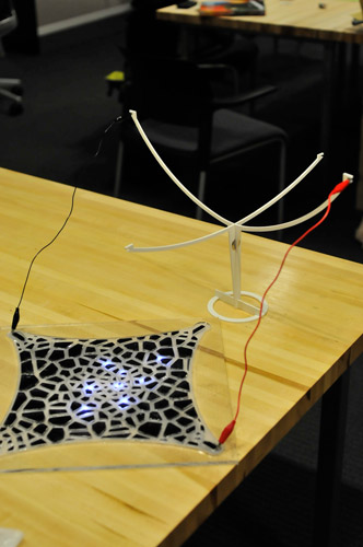 Photo of the lamp base connected to the silicone mold with alligator clips, and lights in the silicone turned on.