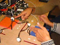 A photo of two students working on what looks like a minature four-way intersection.