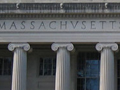 Building with ionic columns and large dome shown from a grassy courtyard.