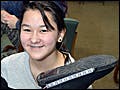 A girl holds up a boot that she is adding lights to.