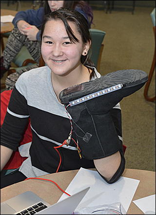 A girl holds up a boot that she is adding lights to.