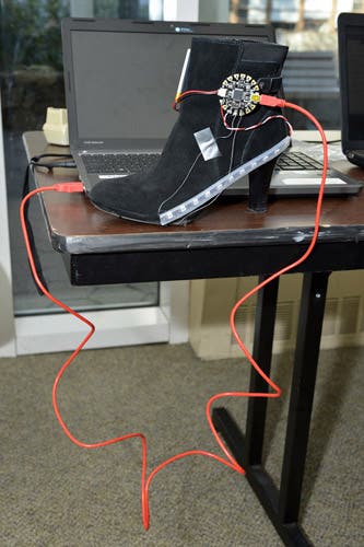A high heeled boot has a pressure sensor and wires attached to it.