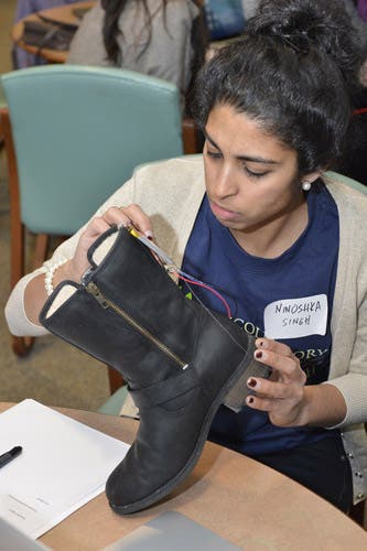 A woman is adding electronic components to a boot.